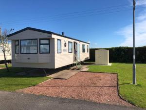 锡勒斯Hylton Park Silloth Caravan Holiday Homes的坐在院子顶上的一个小房子
