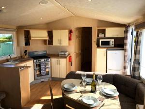 锡勒斯Hylton Park Silloth Caravan Holiday Homes的一间厨房和一间带桌子和沙发的客厅