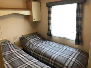 2 camas en una habitación pequeña con ventana en Hylton Park Silloth Caravan Holiday Homes en Silloth