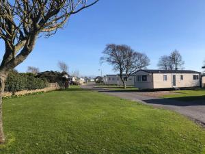 a grassy yard with a house in the distance at Hylton Park Silloth Caravan Holiday Homes in Silloth