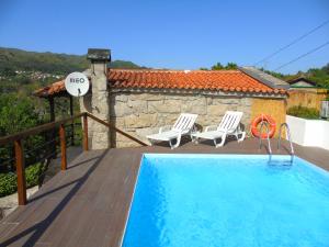 a swimming pool with two chairs and a house at Casa da Carvalheira in Parada