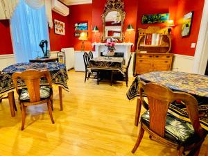 a dining room with two tables and chairs and red walls at Charlotte's Rose Inn in Charlottetown