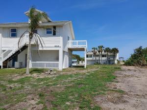 a white house with a palm tree in front of it at Melbourne Beach Florida Townhouse ocean front 1.2 acre property in Melbourne Beach