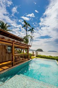 uma piscina em frente a um resort com o oceano em Villa Sapê Pousada em Ubatuba