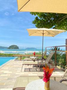 a patio with a table and an umbrella at Villa Sapê Pousada in Ubatuba