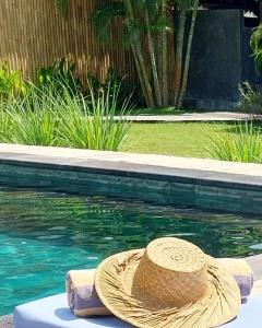 a straw hat sitting next to a swimming pool at Manusia Dunia Green Lodge in Gili Islands