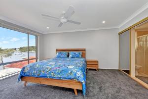 a bedroom with a bed and a large window at Carey Bay 180 degree Water Views and wifi in Rathmines