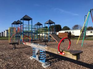 锡勒斯Hylton Park Silloth Caravan Holiday Homes的一个带滑梯和秋千的游乐场的公园