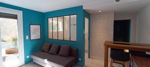 a living room with a couch and a blue wall at Superbe T2 avec grande terrasse en centre ville à 5 min à pieds des Arènes de Nîmes in Nîmes