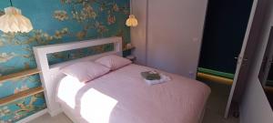 a small bedroom with a pink bed with a hat on it at Superbe T2 avec grande terrasse en centre ville à 5 min à pieds des Arènes de Nîmes in Nîmes