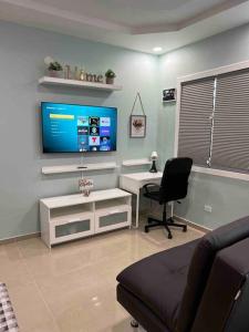 a living room with a tv and a chair and a desk at Palmas View Premium 6 in Humacao