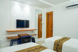 a hotel room with two beds and a flat screen tv at The Paragon Boracay Suites in Boracay