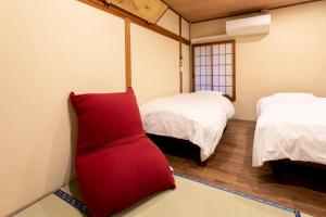 下関市にあるHotel Sumire ふぐ料理を愉しむ料理宿のベッド2台と赤いドレスが備わる客室です。