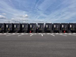una fila de contenedores negros sentados en un estacionamiento en HOTEL R9 The Yard Minokamo, en Minokamo