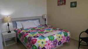 1 dormitorio con 1 cama con una colorida manta de flores en Fully Equipped New 2br Apt–dt–2mins To The Beach, en Sosúa