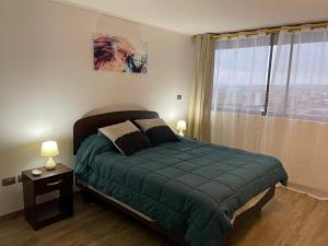 a bedroom with a green bed and a window at Hermoso Departamento entero, sector norte. in Antofagasta