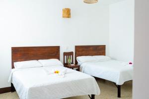 two beds with white sheets and a flower on top of them at Casa Ramona in Flores