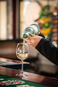a person pouring white wine into a wine glass at Royal Hotel Mandurama in Mandurama