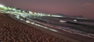 una spiaggia notturna con persone che camminano sulla spiaggia di RECREIO - Alberto Sabin a Rio de Janeiro