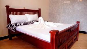 Room in Guest room - Stusky Lark Mini Hotel Seeta في Seeta: سرير خشبي كبير مع أغطية ووسائد بيضاء
