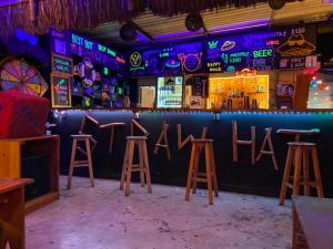 um bar com bancos e placas de néon na parede em Straw Hat Hostel & Rooftop Bar em Tulum