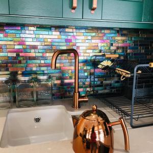 a kitchen sink with a copper tea kettle on it at The Art Attic a Stylish Boutique Apartment in Builth Wells