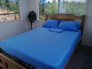 a bedroom with a bed with blue sheets and a window at Islafuerteparadise in Puerto Limón