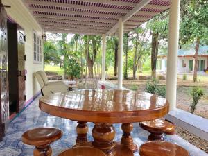 a wooden table sitting on a porch with chairs at นาหินลาดรีสอร์ท Nahinlad Resort in Ban Khok Sawang (2)