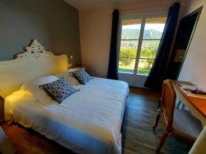 - une chambre avec un lit blanc et une grande fenêtre dans l'établissement Hôtel Les Hauts de Mourèze, à Mourèze