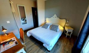 a small bedroom with a bed and a table at Hôtel Les Hauts de Mourèze in Mourèze