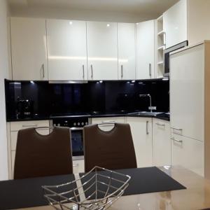 a kitchen with white cabinets and a table and chairs at Strand FeWo Rügen MoonLoft in Binz