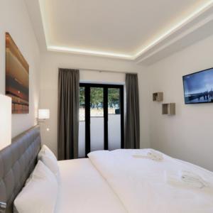 - une chambre avec un lit blanc et une grande fenêtre dans l'établissement Strand FeWo Rügen MoonLoft, à Binz