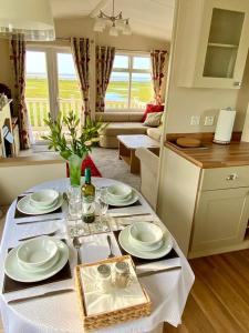 a table with plates and glasses on it in a living room at Ocean Edge Holiday Park Family holiday home with spectacular sea views in Heysham