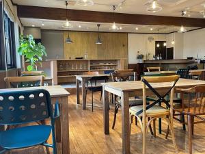 Un restaurante con mesas y sillas y una cocina. en アルパインロッジ, en Inawashiro