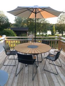 una mesa de madera con sillas y una sombrilla en una terraza en Vanha pappila Hetki Oy en Ähtäri