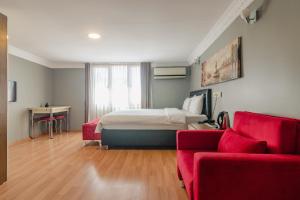 - une chambre avec un lit et un canapé rouge dans l'établissement Zendy Suite Hotel, à Istanbul