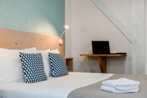 a bedroom with a bed with a laptop on a table at Logis Hotel de France in Mimizan-Plage