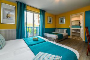 a hotel room with two beds and a balcony at Logis Hotel de France in Mimizan-Plage