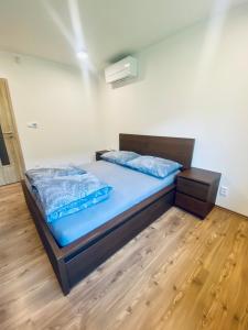 Schlafzimmer mit einem Bett mit blauer Bettwäsche und Holzboden in der Unterkunft Apartmánové domy Kaja, Niko, Simi in Veľký Meder
