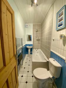 a bathroom with a toilet and a tub and a sink at Underneath the Arches in Penicuik