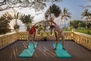 two people doing yoga on mats on a balcony at Amritara The Poovath Beachfront Heritage, Fort Kochi in Cochin