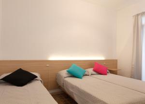 バルセロナにあるアパートメンツ オリビエ バルセロナのカラフルな枕付きのベッド2台が備わる客室です。
