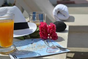 a hat and a drink and flowers on a table at ILIADA-ODYSSEAS RESORT in Perivolos