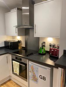 a kitchen with white cabinets and a stove top oven at Entire Studio in picturesque City Islands - Short Walk from Leeds Centre in Leeds