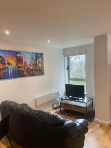 a living room with a leather couch and a table at Entire Studio in picturesque City Islands - Short Walk from Leeds Centre in Leeds