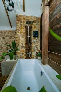 a bath tub in a bathroom with a stone wall at Green Valley Veal Pouch in Kampot