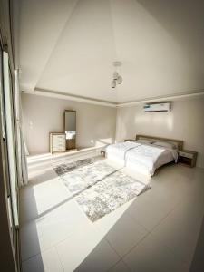 a white bedroom with a bed and a rug at Palm Escape Farmhouse - By Seven Elements in Ras al Khaimah