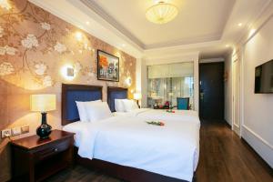 a large bedroom with a large white bed and a table at Golden Legend Boutique Hotel in Hanoi