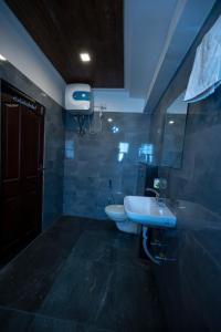 W łazience znajduje się umywalka, toaleta i lustro. w obiekcie HOTEL MITTAL GARDEN w mieście Siliguri