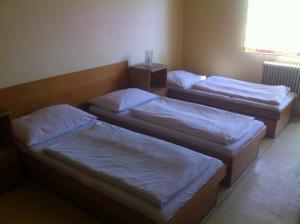 2 camas con sábanas blancas en una habitación en Hotel Bělohlávek, en Holoubkov